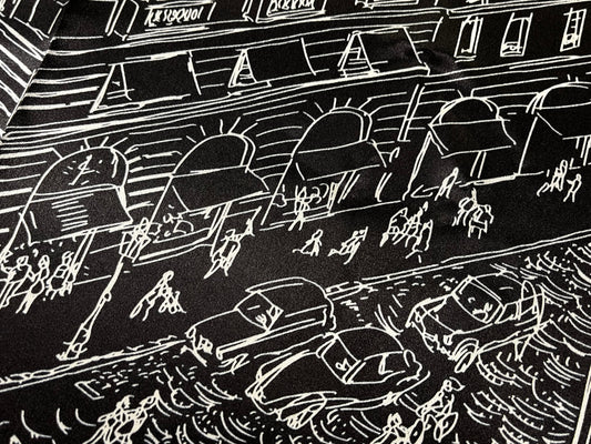 Black and white line drawing of a city street scene with people and cars on a silk scarf.