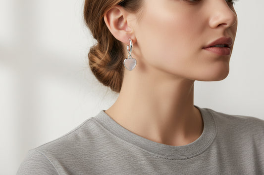 Silver earrings with heart and crescent moon designs on a light background