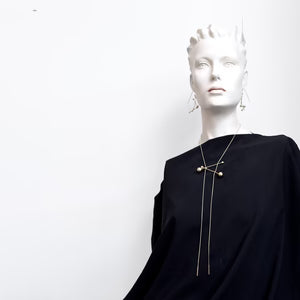 Mannequin wearing a black outfit with a long necklace on a white background