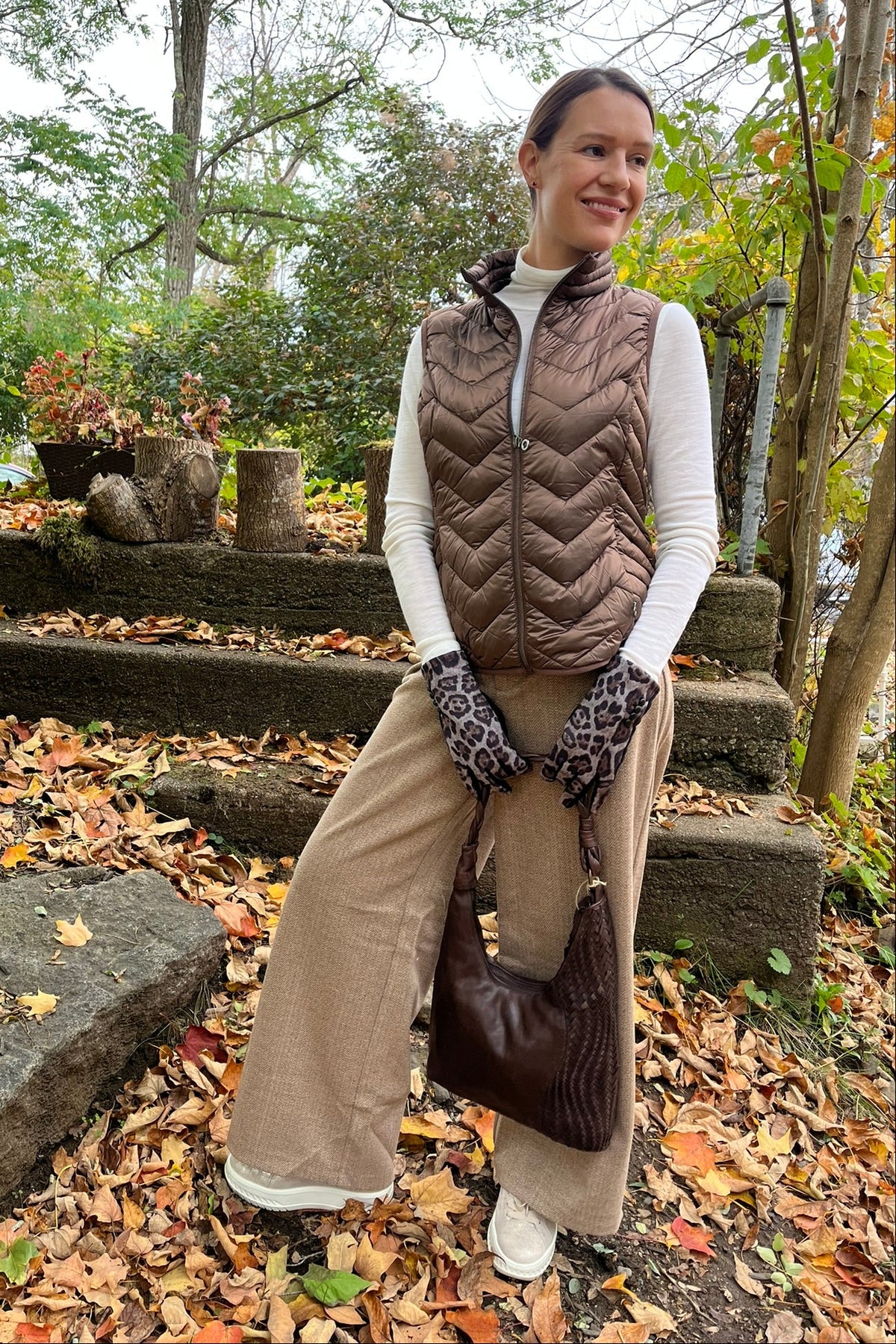 Cari wearing the Junge Louise down vest in brown over a Minus Cally roll neck and Wit & Wisdom Whitney trousers, with the Milo Albany bag and LUV & Co. leopard gloves
