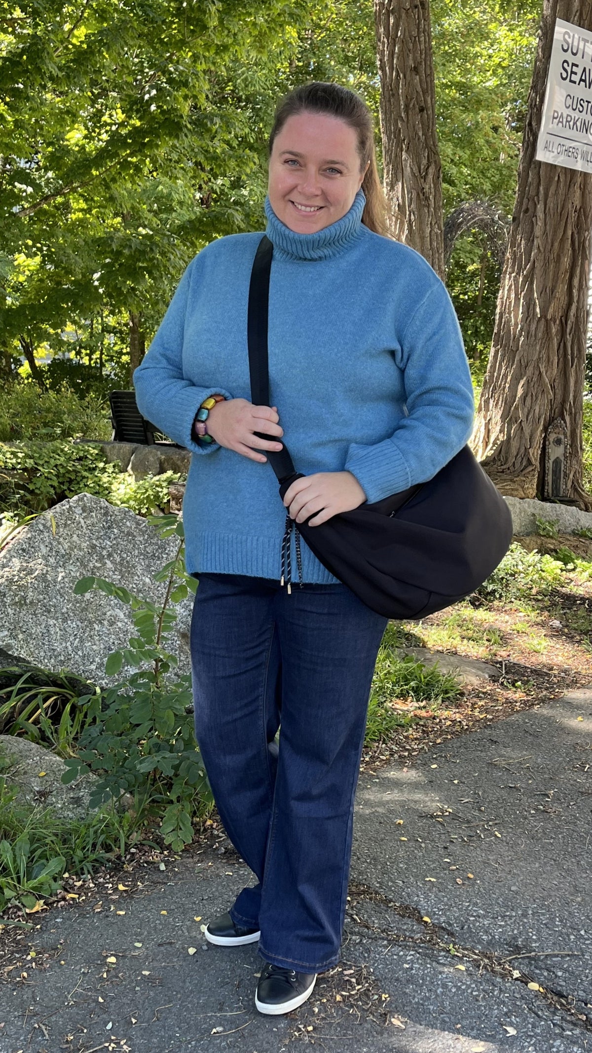 Alma wearing the Echo Verde Dog Walker cowl sweater in azure blue with Carreli baby boot jeans and a Skyla crossbody bag