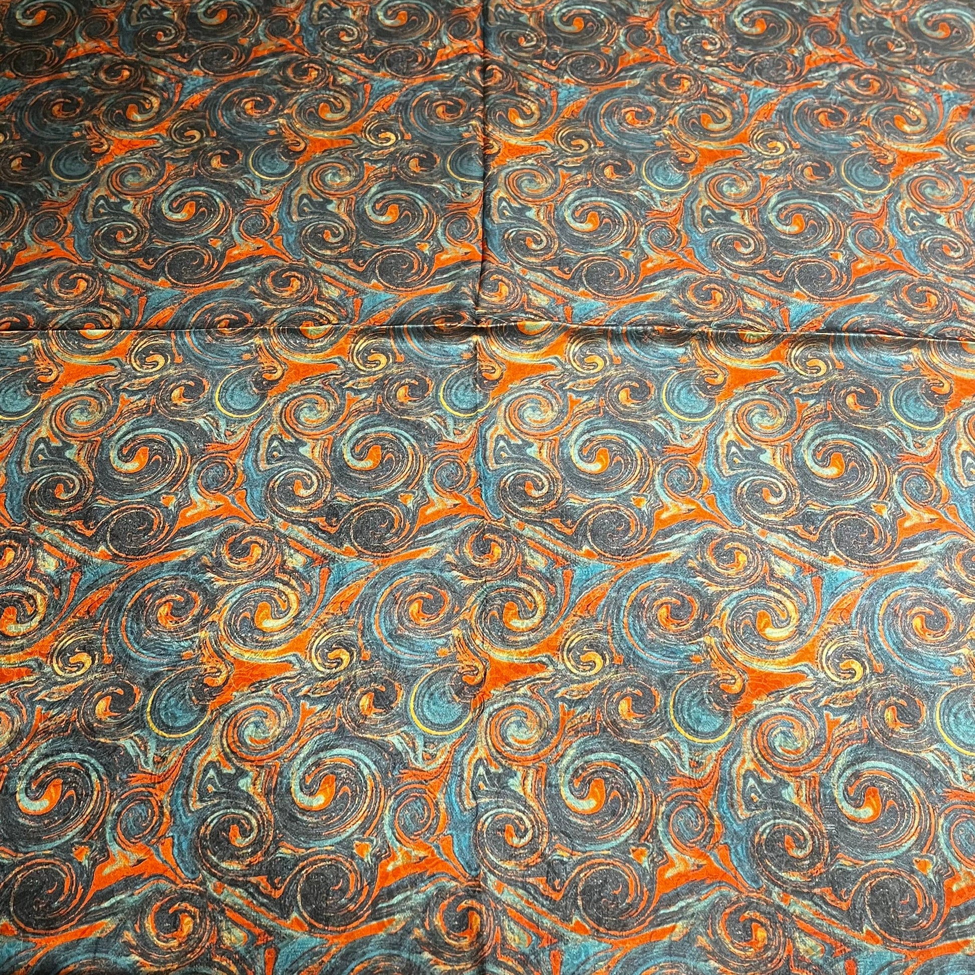 Patterned fabric with swirl designs in blue, orange, and gray on a flat surface.