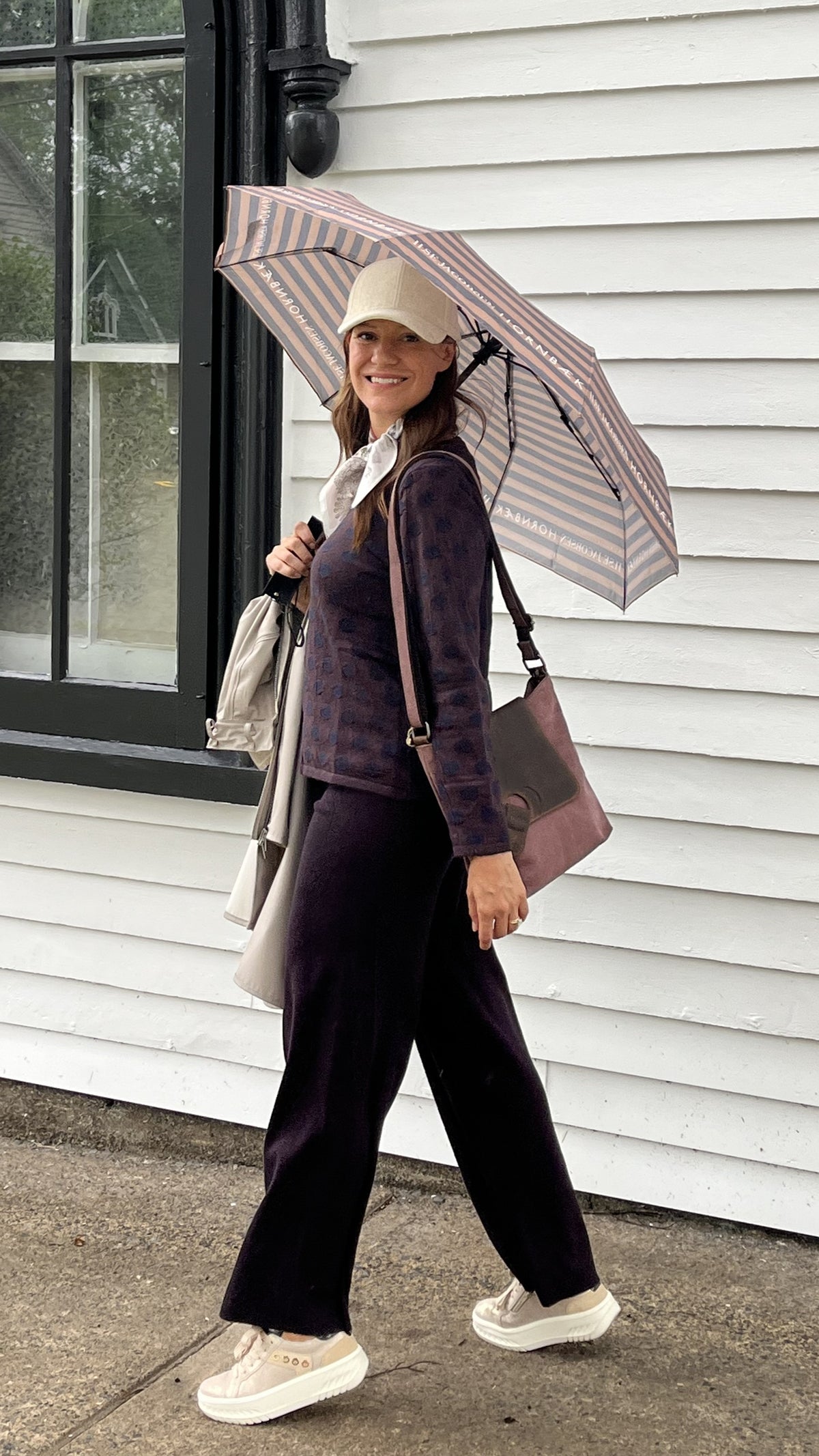 Cari in Lunenburg wearing a Mansted round neck sweater in dark brown with Lyla + Luxe pants, an Ilse Jacobsen raincoat and umbrella