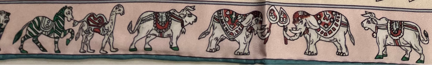 Close-up of a patterned SILK SCARF with intricate designs and animals ON THE BORDER illustrations.