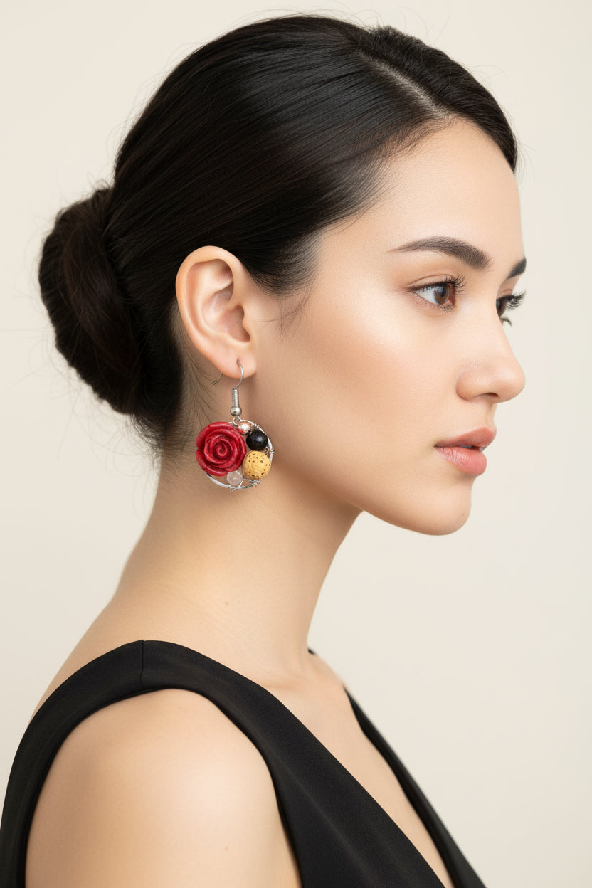 Pair of earrings with red rose-like flowers and black and gold accents on a white background.