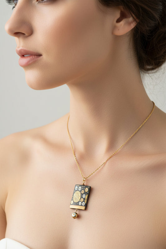 Necklace with a rectangular pendant featuring gold and black design on a white background.