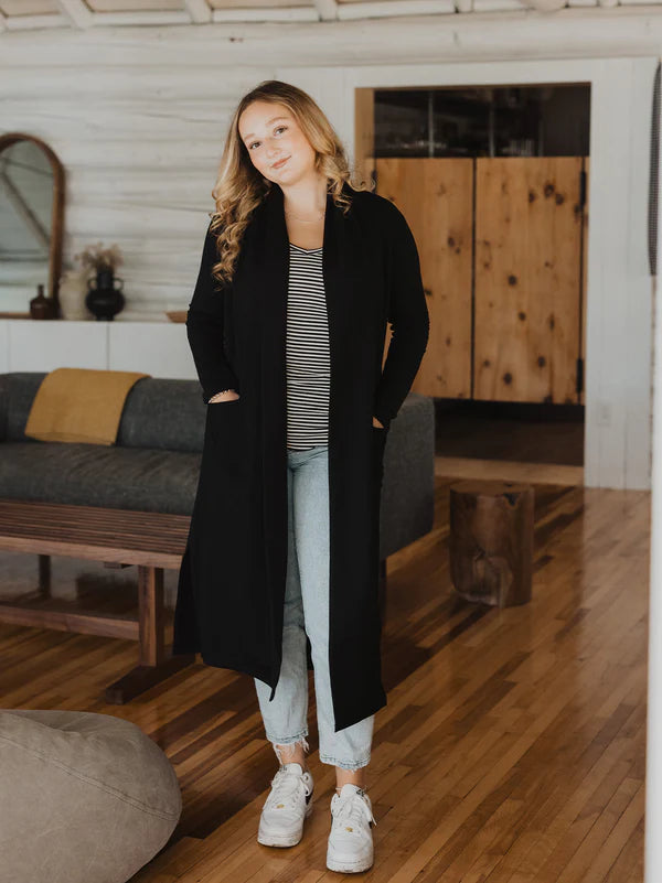 Woman wearing a long black cardigan in a living room setting