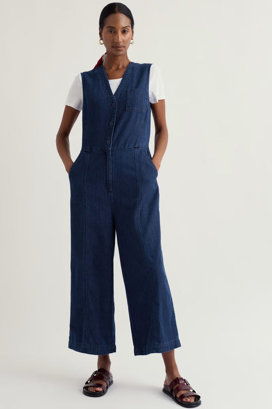 Person wearing a blue denim jumpsuit on a white background