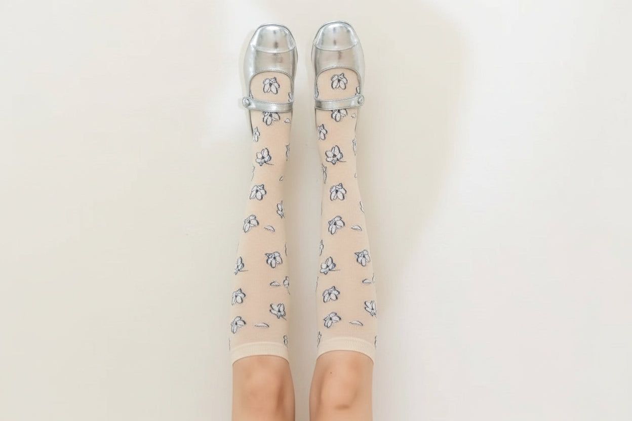 Brown knee-high socks with floral pattern and clear shoes on a beige background