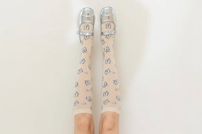 Brown knee-high socks with floral pattern and clear shoes on a beige background