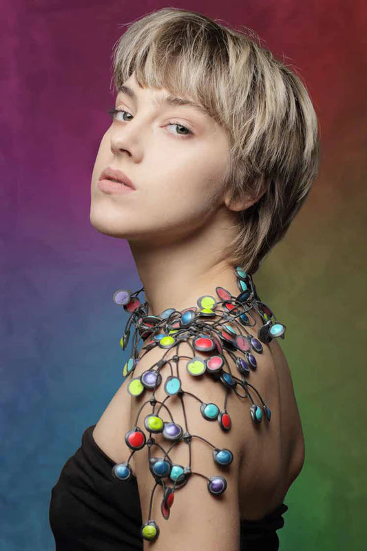Person wearing a colorful, necklace against a gradient background
