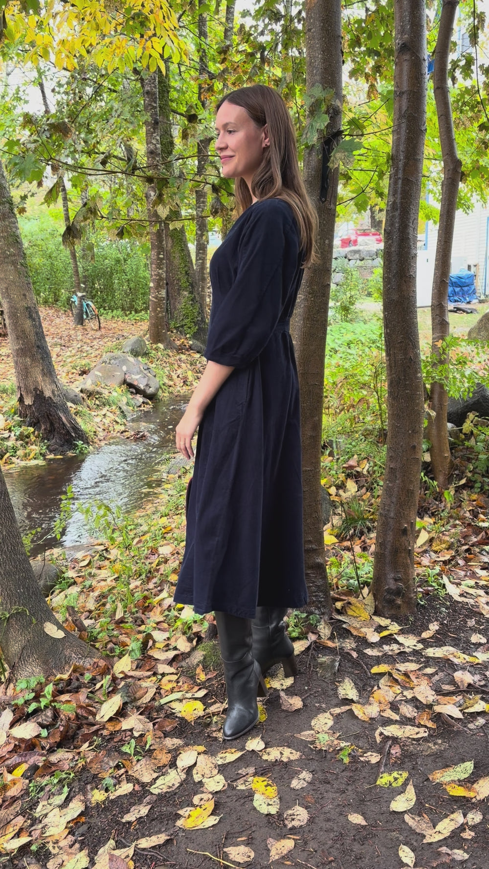 Cari wearing the White Stuff Kate Cord Dress by the stream with the pink plaid Mucros Fiona bag and Spring Moon Starry Night necklace